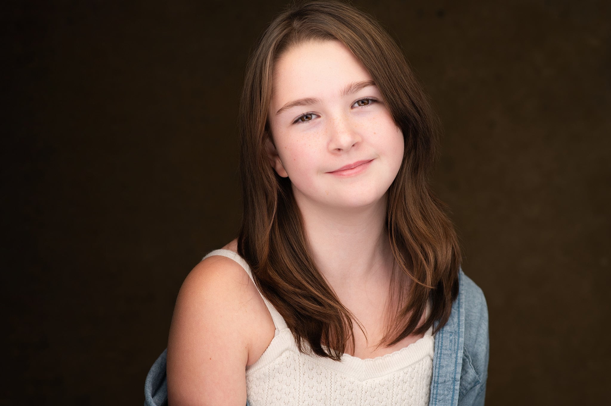 Young actor headshot with natural smile and warm eye contact against soft warm gradient background