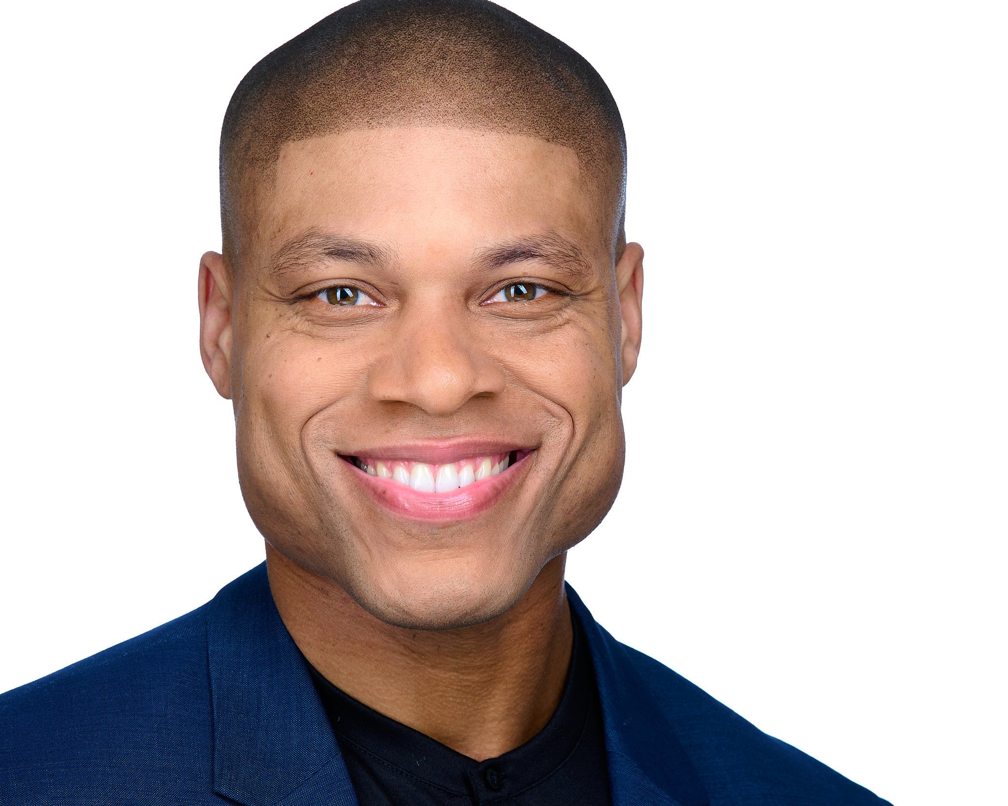 Confident male executive headshot with warm smile in dark blue shirt against white studio backdrop